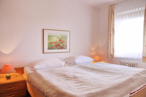 een slaapkamer met een wit bed met 2 lampen en een raam bij Haus Belvedere App 69 WLAN inkl in Grömitz