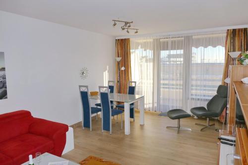- un salon avec un canapé rouge, une table et des chaises dans l'établissement Haus Belvedere App 34 WLAN inkl, à Grömitz
