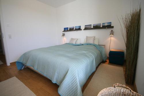 een slaapkamer met een blauw bed met 2 verlichting aan de muur bij Seeblick Seeloft 2 inkl WLAN in Grömitz