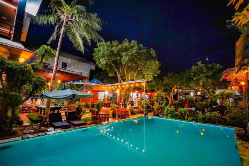 a swimming pool at night with chairs and tables at Phong Nha Tuan Garden House in Phong Nha