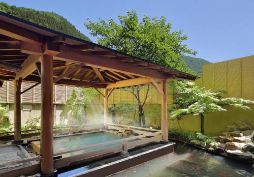 a swimming pool under a wooden pavilion next to a pond at Tachibanaya in Tsuruoka