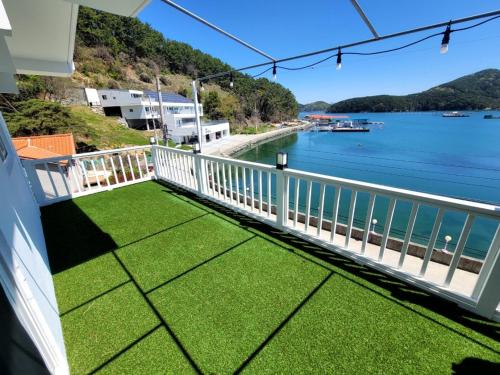 balcón con césped verde y vistas al agua en Hahahoho Friend Pension en Tongyeong