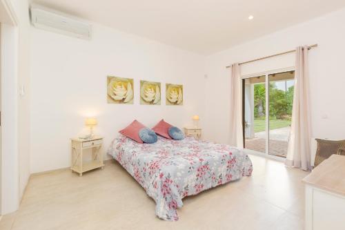 - une chambre blanche avec un lit et une fenêtre dans l'établissement Villa Jardim do Paraiso, à Mexilhoeira Grande
