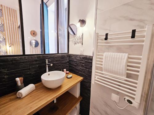 une salle de bain avec un lavabo blanc et un miroir dans l'établissement Le jardin vert, paisible maison de ville, à Angoulême