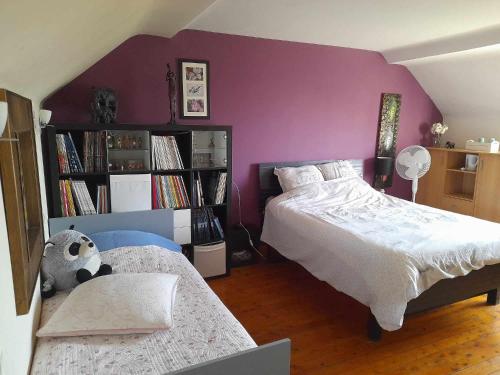 a bedroom with two beds and a purple wall at Au Moulin de la Tour in La Malmaison