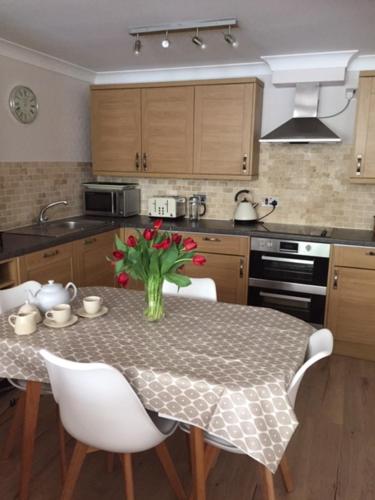 a kitchen with a table with a vase of flowers on it at Carbis Bay luxury ground floor flat close to beach in Carbis Bay