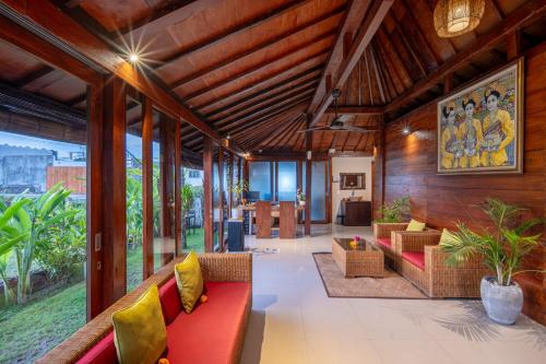 a living room with a red couch and yellow pillows at Nyanyi Sanctuary Villa by Ini Vie Hospitality in Tanah Lot