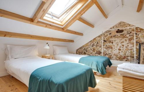 two beds in a room with a stone wall at Classic Lisbon Homes: Bright & Central in Belém in Lisbon