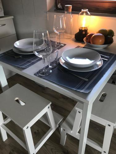 a table with plates and wine glasses on it at Lovas Udvarház Ezüst Zabla Apartman Piliscsaba in Piliscsaba