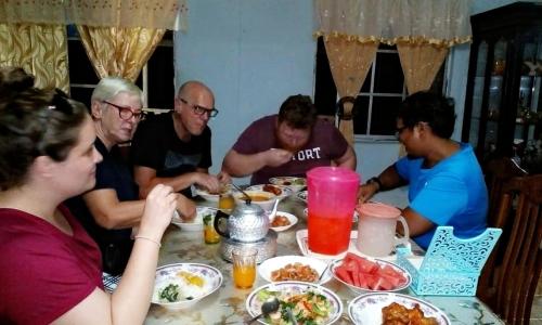 un grupo de personas sentadas alrededor de una mesa comiendo comida en Homestay Teratak Kayu kota Aur en Kepala Batas