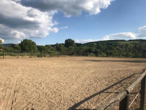 a dirt field with a fence in the distance at Lovas Udvarház Ezüst Zabla Apartman Piliscsaba in Piliscsaba