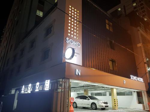 a car parked in front of a building with a clock at Soho Hotel in Busan