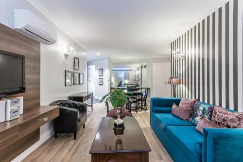 a living room with a blue couch and a table at Romney Park Luxury Apartments in Cape Town