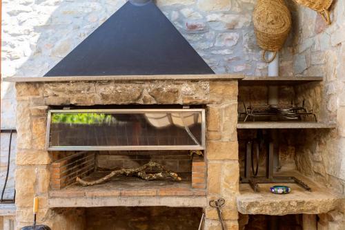 a stone fireplace with a blue roof at 21 Sleeps Private Pool Villa & BBQ Near Barcelona in Rocafort