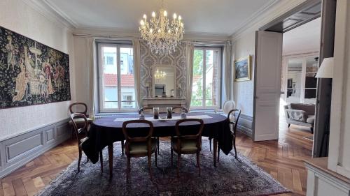 une salle à manger avec une table, des chaises et un lustre dans l'établissement Résidence de la Marquise, à Nancy