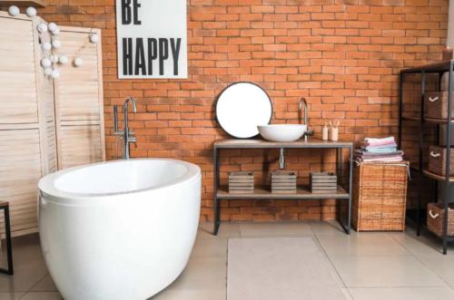 a bathroom with a white tub and a brick wall at Happy 1 Hotel Binh Duong in Bến Cát