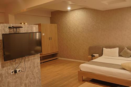 a hotel room with a bed and a flat screen tv at Hotel Shree Meghdootam in Bhopal