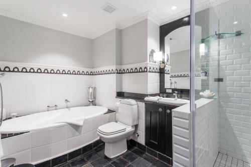 a bathroom with a tub and a toilet and a sink at Romney Park Luxury Apartments by The Stay Collection in Cape Town
