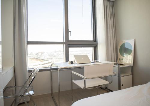 a bedroom with a bed and a desk with a laptop at UH FLAT The SONGDO in Incheon