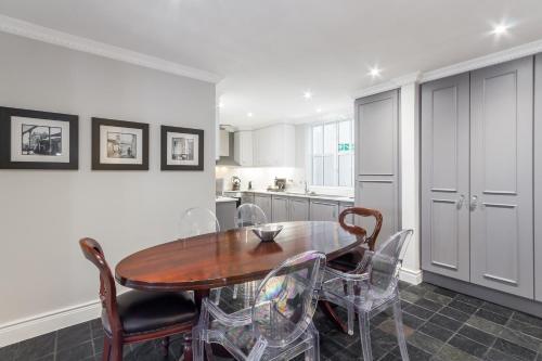 a kitchen with a wooden table and chairs at Romney Park Luxury Apartments by The Stay Collection in Cape Town
