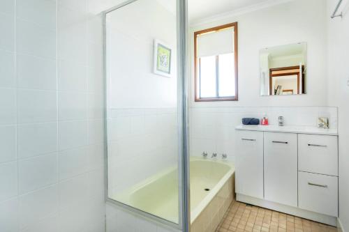 a white bathroom with a tub and a sink at Cables Beach House Lancelin in Lancelin