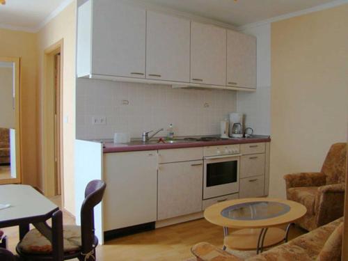 eine Küche mit weißen Schränken und einem Tisch im Zimmer in der Unterkunft Ferienwohnungen Mülling in Heringsdorf