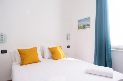 Cama blanca con almohadas amarillas y ventana en [Twins apartament Giallo]clima en Génova