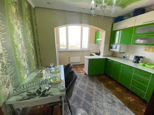 a kitchen with green cabinets and a table with chairs at Quiet appartment in Bishkek city in Bishkek