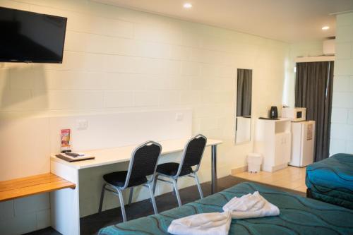 a room with a desk and two chairs and a bed at Mundubbera Motel in Mundubbera
