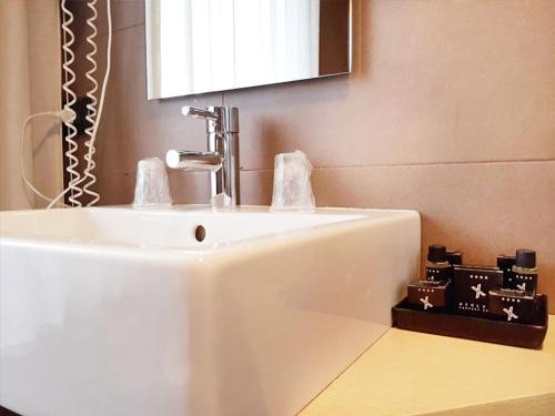 een witte wastafel in een badkamer met een spiegel bij Axolute Comfort Hotel Como - Cantù in Cantù