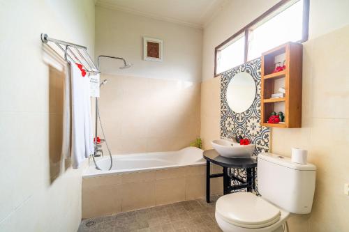 a bathroom with a tub and a toilet and a sink at Om Ham Retreat and Resort in Ubud