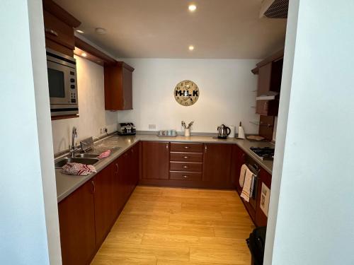 uma cozinha com armários de madeira e piso de madeira em Comfy Two Bedroom Apartment Right In The City Centre em Glasgow