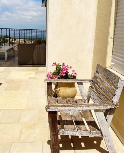 a wooden bench with a pot of flowers on a balcony at Benichuta in Mitzpe Hila