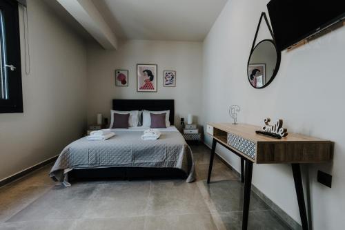 a bedroom with a bed and a desk with a mirror at Pearl Apartel in Volos