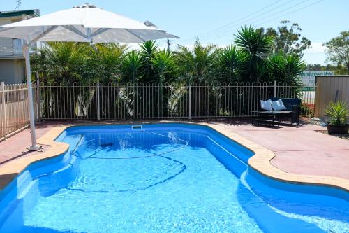 una piscina con sombrilla en un patio en Mundubbera Motel en Mundubbera
