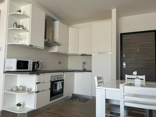 a kitchen with white cabinets and a table and a microwave at RED SKY APARTMENT - PORTA DI ROMA in Rome
