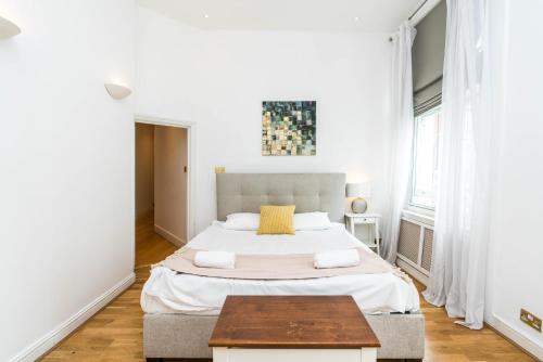 een witte slaapkamer met een groot bed en een tafel bij Spacious 2 bedroom / Gloucester Road / Kensington in Londen