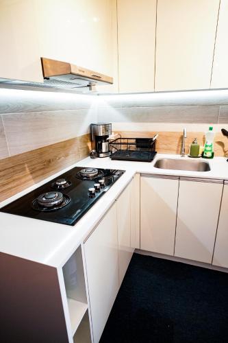 a kitchen with a stove top oven next to a sink at Modern Designed Studio Condo Near Ayala Centrio in Cagayan de Oro