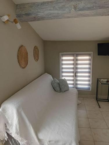 une chambre avec un lit blanc et une fenêtre dans l'établissement Studio terrasse vue cathédrale, à Narbonne