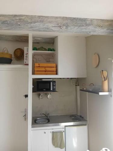 une petite cuisine avec des armoires blanches et un micro-ondes dans l'établissement Studio terrasse vue cathédrale, à Narbonne