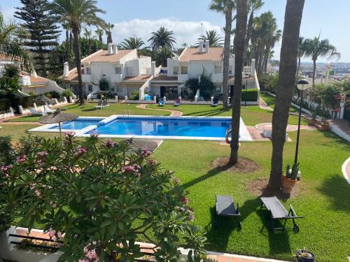 una casa con piscina y palmeras en MAGNIFICO CHALET UNICO JUNTO AL MAR CALETA DE VELEZ, en Caleta de Vélez