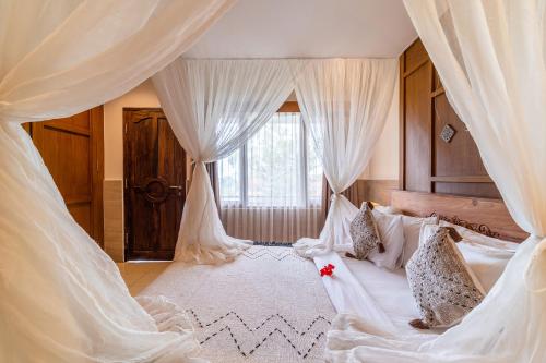 a bedroom with a canopy bed with white curtains at Om Ham Retreat and Resort in Ubud