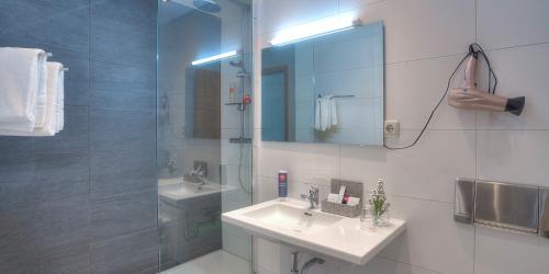 a bathroom with a sink and a shower with a mirror at ACHAT Hotel Frankfurt Maintal in Maintal