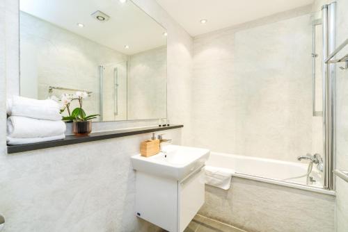 La salle de bains blanche est pourvue d'un lavabo et d'une baignoire. dans l'établissement Spacious 2 bedroom / Earls Court / Kensington, à Londres