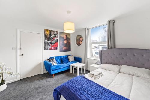 1 dormitorio con 1 cama azul y 1 sofá azul en Contemporary apartment by train station and city centre en Kent