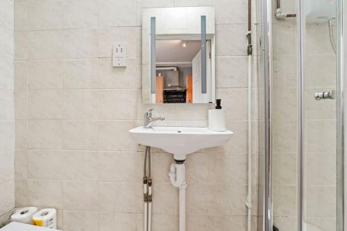 a bathroom with a sink and a shower with a mirror at Contemporary apartment by train station and city centre in Kent