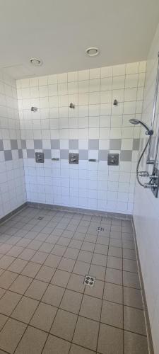 uma casa de banho com um chuveiro com azulejos brancos em Camping Sportzentrum Zeltweg - a silent alternative em Zeltweg