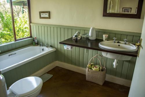 a bathroom with a tub and a sink and a toilet at Three Tree Hill Lodge in Bergville