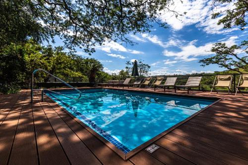 a swimming pool on a wooden deck with chairs at Three Tree Hill Lodge in Bergville