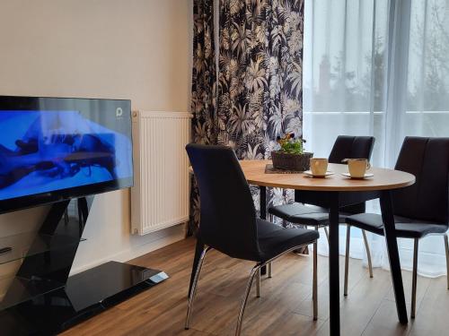 a dining room with a table with chairs and a television at Comfy apartment near the sea in G ski in Gąski